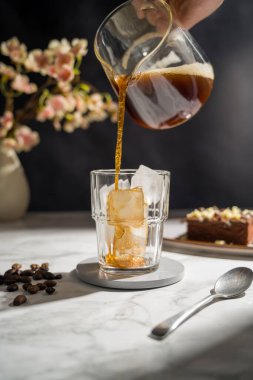 Buzlu bir bardağa koyu kahve dolduruyorum..