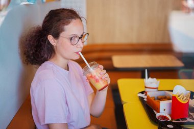 Birleşik Krallık, Corby, 2 Temmuz 2025: McDonalds 'da fast food yiyen genç kız, patates kızartması ve sallanan içecekler