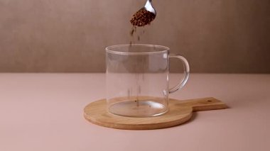 Şeffaf cam bardağa anlık kahve dökülüyor, kavrulmuş kahve çekirdekleri..