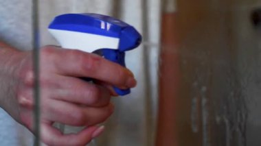 Lastik eldivenlerle cam duş perdesini temizliyorum.