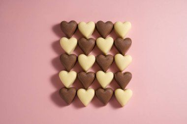 Kalp şeklinde çikolata parçaları pembe arka planda, soyut yemek aşk arka planında