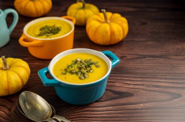 Seramik kaselerde kabak çorbası, ahşap arka plan, taze balkabakları. Sonbahar yemekleri.