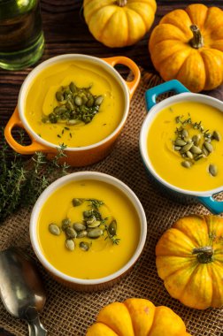 Seramik kaselerde kabak çorbası, ahşap arka plan, taze balkabakları. Sonbahar yemekleri.