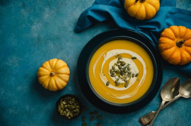 Mavi kapta balkabağı çorbası, mavi arka plan. Sonbahar yemekleri.