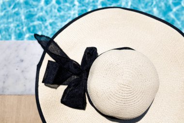 Hasır bir şapka havuzun kenarına konur.