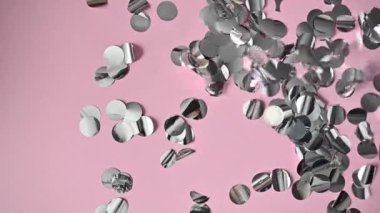 Pembe arka planda ağır çekimde gümüş renkli konfeti patlaması. Noel ve yeni yıl tatili tasarımı veya doğum günü.