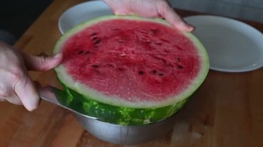 Eller canlı bir karpuzu ikiye böler. Yaz piknikleri için mükemmel, taze meyve kesme teknikleri sergileniyor.