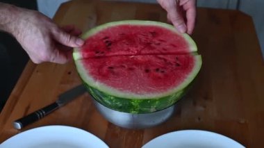 Ahşap bir masada taze karpuz dilimleyip servis eden eller meyvelerin canlı rengini renklendiriyor.