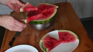 Ahşap bir masada taze karpuz dilimleyip servis eden eller meyvelerin canlı rengini renklendiriyor.
