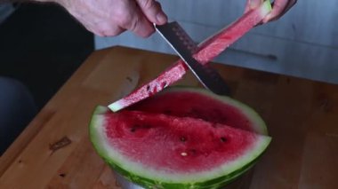 Ahşap bir masada taze karpuz dilimleyip servis eden eller meyvelerin canlı rengini renklendiriyor.