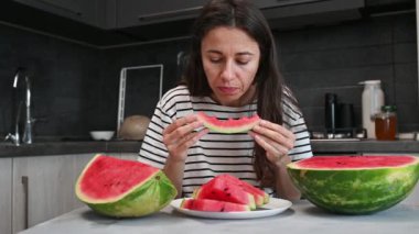 Karpuz yiyen bir kadın, yüzüne ve ağzına yakın çekim. çekici genç vejetaryen kadın ev mutfağında, sağlıklı yaşam tarzı ve iyi ruh hali.