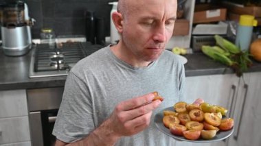 Meyve eriği yiyen bir adam, yüzüne ve ağzına yakın çekim. çekici genç vejetaryen kadın ev mutfağında, sağlıklı yaşam tarzı ve iyi ruh hali.