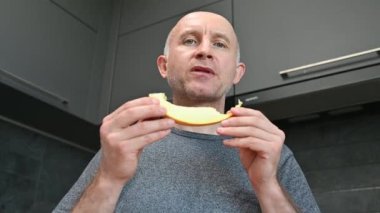 Yakından kavun yiyen bir adam. Sağlıklı beslenme, meyveler akşam yemeğinde vejetaryen yemekleri, organik sağlıklı çiğ yiyecekler..