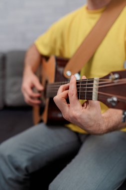Gitarist ofiste akustik gitara para ödüyor. Erkek müzisyen kanepede oturuyor ve müzik aleti çalıyor..