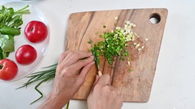 Yeşil soğan mutfakta bıçakla kesilir. Sağlıklı sebze salatası konsepti. Mutfaktaki yeşil soğan. Yaşam tarzını yakından keserek dilimleyin.