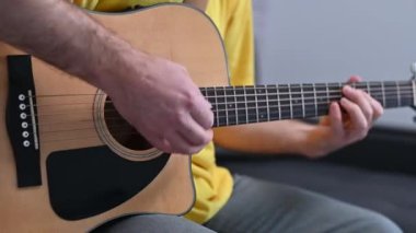 Müzisyen elleri gitar tellerine basar, ahşap akustik enstrümandaki tutkulu performans sırasında melodik ses üretir.