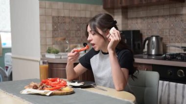 Renkli sebzeler, taze meyve ve peynir içeren sağlıklı bir kahvaltıyı zevkle izleyen genç bir kadın.