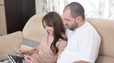 Romantik çift kucaklaşıyor, aşk mektupları okuyor ve sevgililer günü kutlamaları sırasında oturma odasındaki kanepede samimi anlar paylaşıyor.
