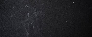 Yıpranmış tebeşir tozlu yüzey derin çizikler taşıyor, karanlık arka plana karşı yaşlanma ve fiziksel sıkıntıları ortaya çıkarıyor.