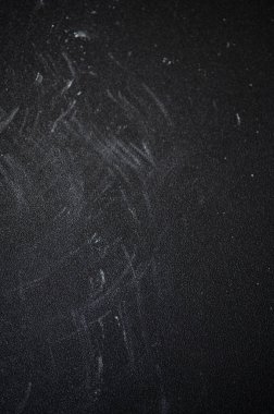 Yıpranmış tebeşir tozlu yüzey derin çizikler taşıyor, karanlık arka plana karşı yaşlanma ve fiziksel sıkıntıları ortaya çıkarıyor.