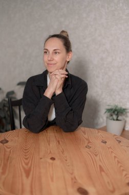 Genç bir kadın, gri bir kanepede rahat rahat oturarak evde vakit geçirmekten zevk alıyor. Gülümsüyor ve rahat görünüyor. Sıcak bir atmosferde yumuşak, doğal bir ışıkla çevrili..