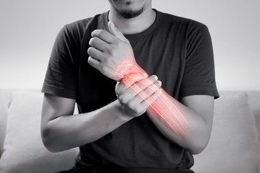 Kolunda osteoporoz belirtileri olan bir adam gri arka planda bilek ağrısı çeken insanlar. Dirsek eklem hastalıkları.