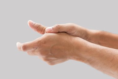 A man with thumb pain on a gray background.