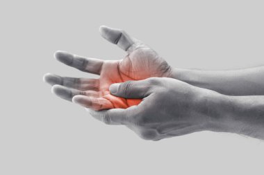 A man grab hand palm because the hand palm was injured. Hand pain. On a gray background.