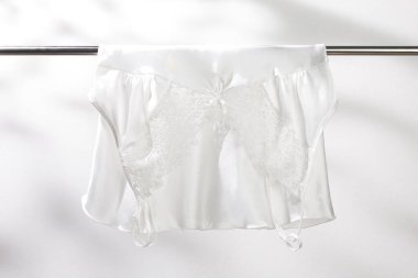 Beyaz saten pijamalar paslanmaz çelik çamaşır ipinde asılı..
