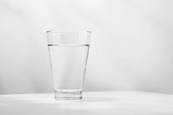 Pure water in the glass is on the white wooden table.