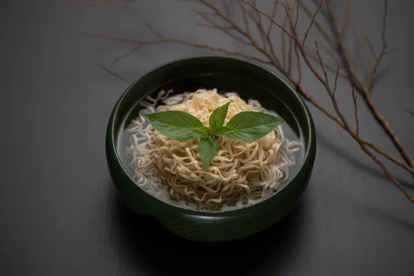 Instant noodles in a ceramic bowl in Japanese ceramic style on a black wooden table.