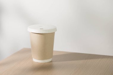 Tek kullanımlık kağıt kahve fincanı kafedeki ahşap bir masada..