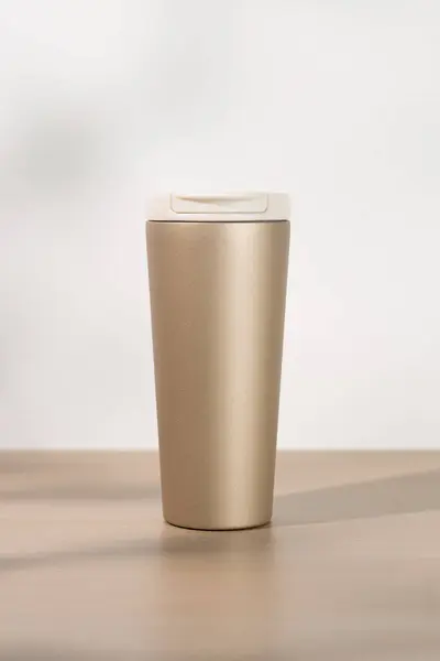 Gold stainless steel tumbler size 20 ounce on wooden table.