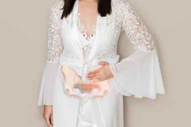 A Woman in a white satin nightgown has waist pain because the pelvis has a problem. clipart