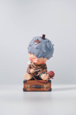Klasik bir valizin üzerinde uyuyan bir çocuk figürü. HIRONO Reshape figürleri, POPMART tarafından ahşap bir masa ve beyaz zemin üzerinde satılan bir iyileştirme serisidir..