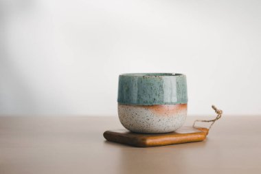 Deniz mavisi ve benekli bir bardak, ahşap bir tabanda özenle hazırlanmış, minimalist güzelliği temsil ediyor..