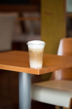 Cezbedici bir buzlu kapuçino, antika bir kafede, ahşap bir masanın üzerinde duruyor..