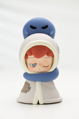 Bangkok, Tayland - Ekim 2024: Mavi bir ruh ya da hayalet tarafından kucaklanan başını ve vücudunu battaniyeyle örten bir çocuk figürü. Ruhun kuyruğu çocuğun boynuna dolanır..