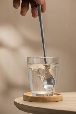 Bir el, suyu kaşıkla karıştırıp Himalaya tuzunu karıştırıyor. Bu karışım sağlık yararları için aralıklı oruç sırasında, temel mineralleri sağlamak ve detoksifikasyona yardımcı olmak için kullanılır..