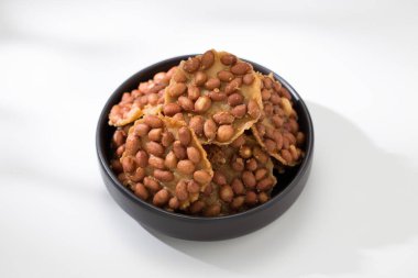 Birkaç parça yuvarlak, kızarmış fıstık siyah, yuvarlak bir seramik kasede beyaz ahşap bir masaya konur. Geleneksel Tayland atıştırmalığı..