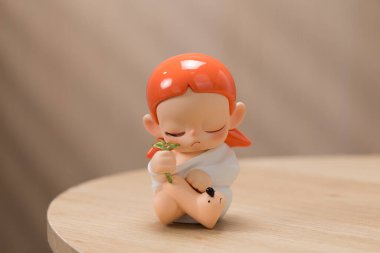 Pop Mart Zsiga Tomurcuklanma Hayatı. Turuncu saçlı bir bebek elinde tutulan minyatür yeşil bir ağaca bakarken yakalandı. Sıcak ve davetkar bir ev ortamının ortasında..