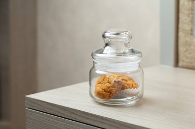 Masadaki tek bir kavanozda birkaç kurabiye var. Sakin, sade bir ortam ve rahatlatıcı bir atıştırmalık sözü veriyor..