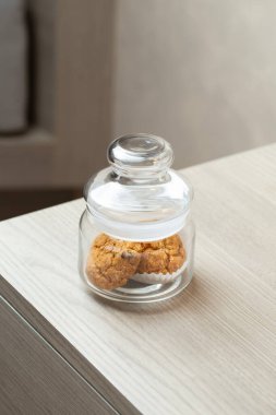 Masadaki tek bir kavanozda birkaç kurabiye var. Sakin, sade bir ortam ve rahatlatıcı bir atıştırmalık sözü veriyor..