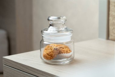 Masadaki tek bir kavanozda birkaç kurabiye var. Sakin, sade bir ortam ve rahatlatıcı bir atıştırmalık sözü veriyor..