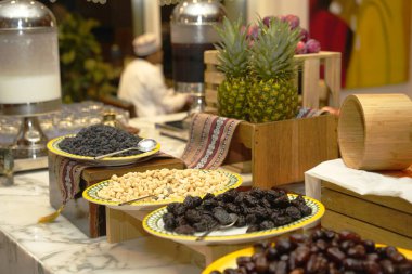 A vibrant buffet display featuring an assortment of dried fruits dates, nuts, and fresh pineapple, elegantly arranged and inviting guests to savor a taste of tropical indulgence. clipart