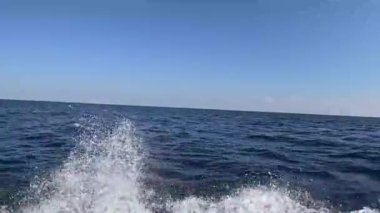 Derin mavi dalgaların üzerinden, Muscat, Umman 'daki Mina Al Fahal' de açık bir gökyüzü ile kayıktan çekilen gelgit dalgalarının yakın görüntüsü..