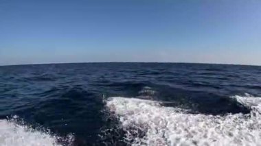 Uçsuz bucaksız okyanus manzarası, yumuşak dalgalar açık mavi gökyüzünün arka planına beyaz izler bırakıyor, Muscat, Umman 'daki Mina Al Fahal' da sükuneti temsil ediyor..
