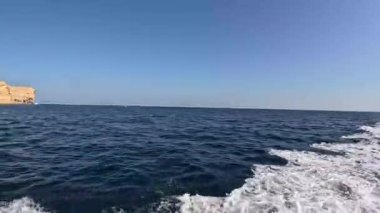 Derin mavi dalgaların üzerinde kayıktan çekilen gelgit dalgalarının yakından görüntüsü, yukarıda açık bir gökyüzü, Muscat, Umman 'daki Mina Al Fahal' da deniz yaşamının özünü somutlaştırıyor..