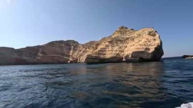 Muazzam bir kaya oluşumu sakin sulardan fışkırıyor, eşsiz doku ve renkler sergiliyor, Muscat, Umman 'daki Mina Al Fahal' ın büyüleyici doğal güzelliğini yansıtıyor..