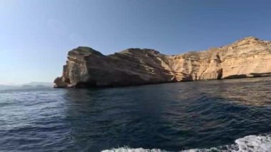 Yükselen kaya oluşumları durgun gök mavisi suların üzerinde dramatik bir şekilde yükselir ve Muscat, Umman 'daki Mina Al Fahal' da doğanın saf güzelliğini yansıtan çarpıcı bir manzara yaratır..